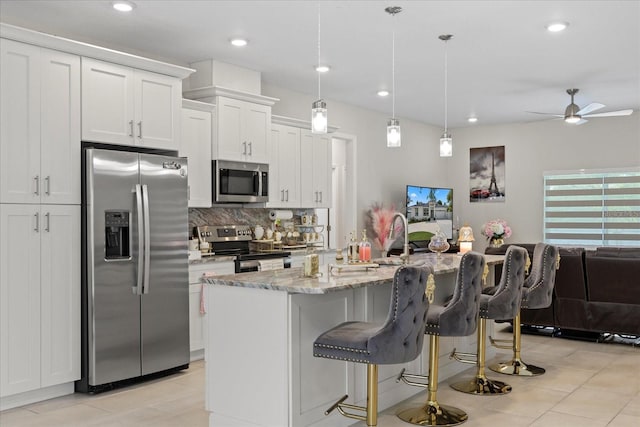 19212 Sunlake Blvd, Lutz, FL 33558 - kitchen featuring appliances with stainless steel finishes, backsplash, a breakfast bar, a ceiling fan, and light stone countertops