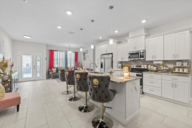 19212 Sunlake Blvd, Lutz, FL 33558 - kitchen featuring appliances with stainless steel finishes, backsplash, a kitchen bar, white cabinetry, and recessed lighting