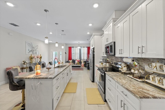 19212 Sunlake Blvd, Lutz, FL 33558 - kitchen featuring appliances with stainless steel finishes, a sink, a breakfast bar, an island with sink, and white cabinets