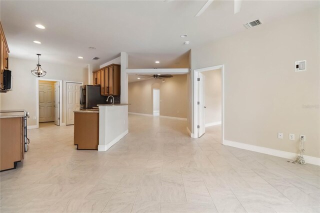 2262 Lune Ct, Melbourne, FL 32904 - kitchen with a ceiling fan, fridge, recessed lighting, brown cabinetry, and baseboards