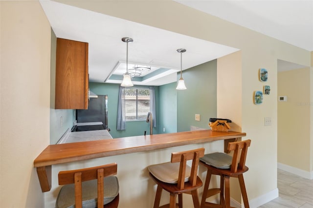 143 Lakeside Dr Unit 143, Oldsmar, FL 34677 - kitchen with freestanding refrigerator, hanging light fixtures, baseboards, brown cabinets, and a sink