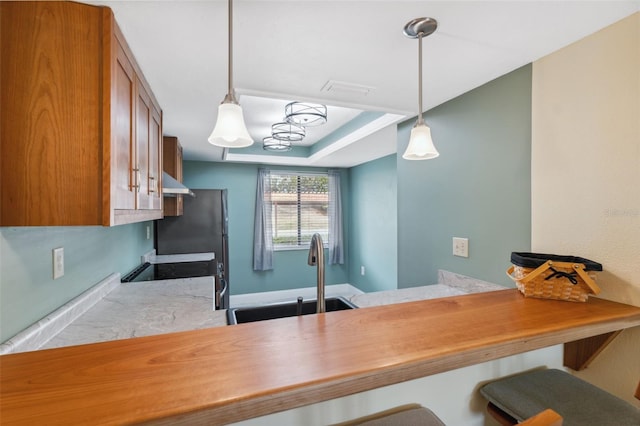 143 Lakeside Dr Unit 143, Oldsmar, FL 34677 - kitchen featuring a sink, brown cabinetry, extractor fan, a breakfast bar, and pendant lighting