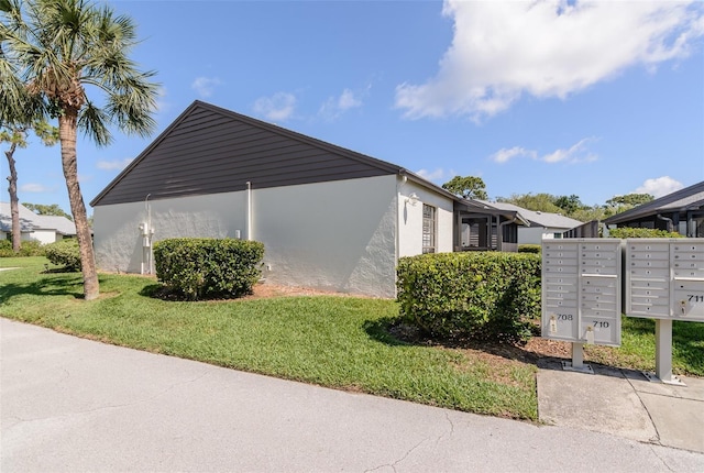 322 Windrush Loop Unit 22, Tarpon Springs, FL 34689 - view of side of property featuring mail area, stucco siding, and a yard