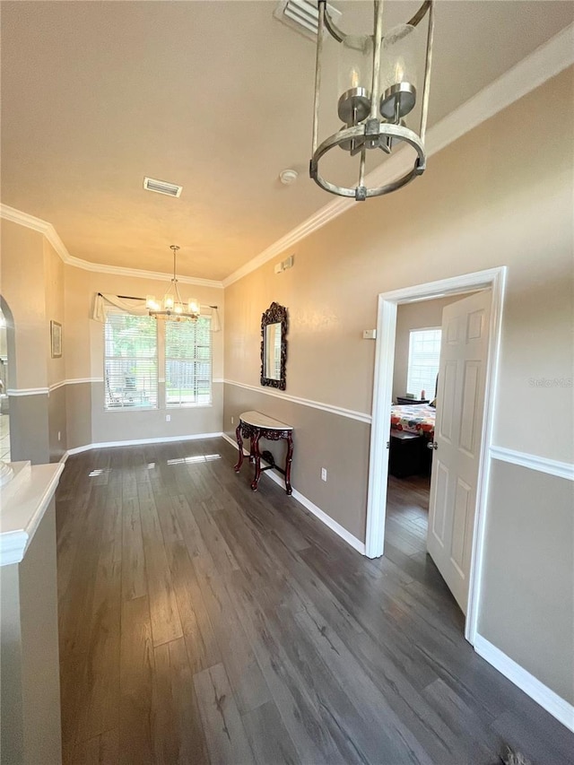 2244 NW 101st St, Gainesville, FL 32606 - unfurnished dining area with a chandelier, crown molding, dark wood-style flooring, arched walkways, and baseboards