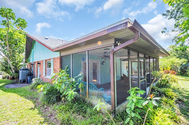 3224 Hilary Cir, Palm Harbor, FL 34684 - back of property with a sunroom, brick siding, central AC unit, and ceiling fan