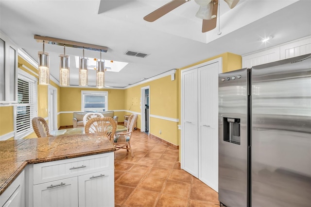 3224 Hilary Cir, Palm Harbor, FL 34684 - kitchen featuring stainless steel fridge with ice dispenser, white cabinetry, light tile patterned floors, ceiling fan, and hanging light fixtures