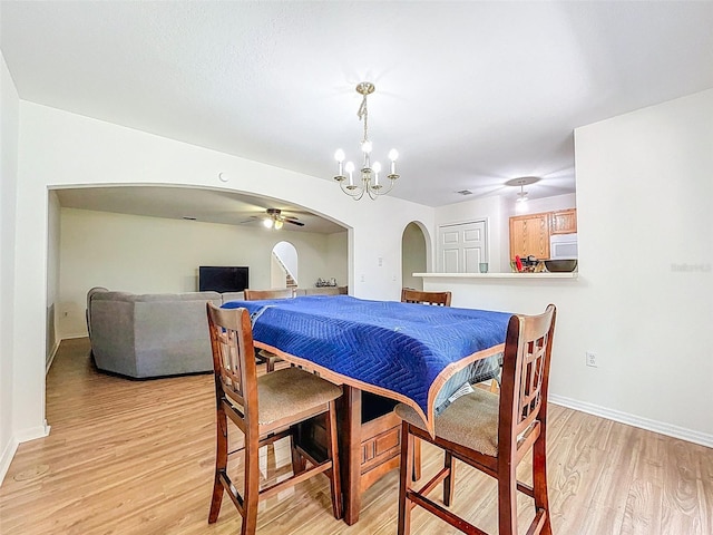 4732 Ashburn Pond Way, Tampa, FL 33610 - dining room featuring arched walkways, light wood-type flooring, a ceiling fan, and a chandelier