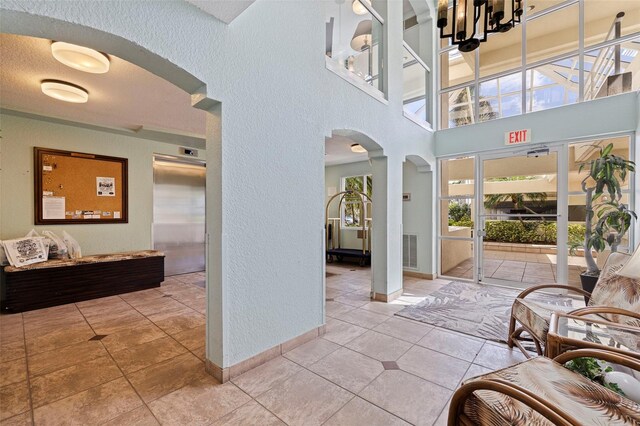 6105 Bahia Del Mar Cir Unit 683, Saint Petersburg, FL 33715 - foyer with arched walkways, a textured wall, decorative columns, baseboards, and a towering ceiling