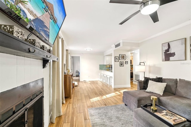 2969 Bonaventure Cir Unit 104, Palm Harbor, FL 34684 - living area featuring light wood-style floors, ornamental molding, ceiling fan, baseboards, and a tile fireplace