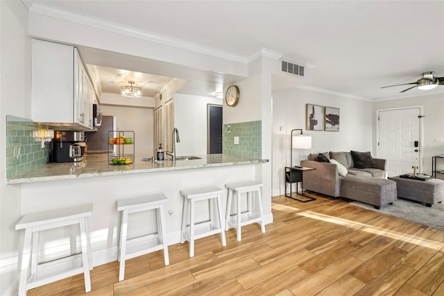 2969 Bonaventure Cir Unit 104, Palm Harbor, FL 34684 - kitchen featuring a sink, a peninsula, light wood finished floors, a kitchen bar, and decorative backsplash