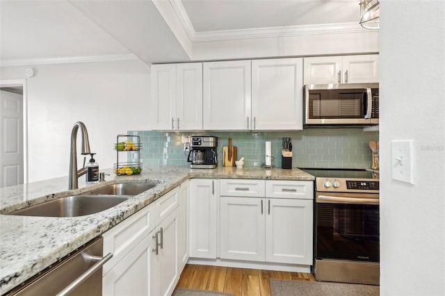 2969 Bonaventure Cir Unit 104, Palm Harbor, FL 34684 - kitchen with stainless steel appliances, a sink, crown molding, light wood-style flooring, and white cabinets
