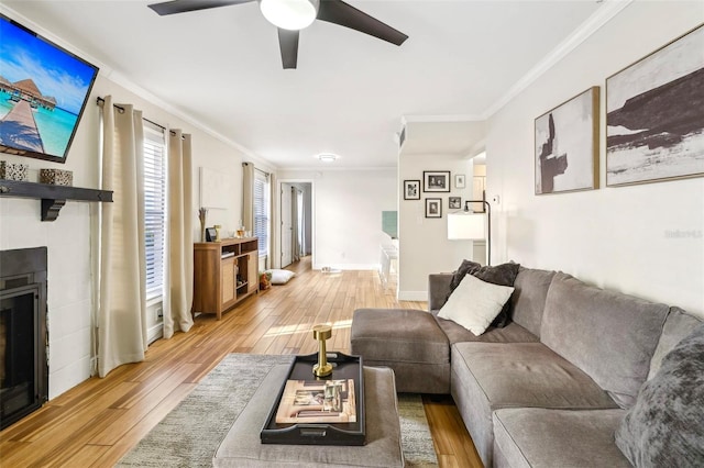 2969 Bonaventure Cir Unit 104, Palm Harbor, FL 34684 - living room featuring light wood-style flooring, ornamental molding, a ceiling fan, a tile fireplace, and baseboards