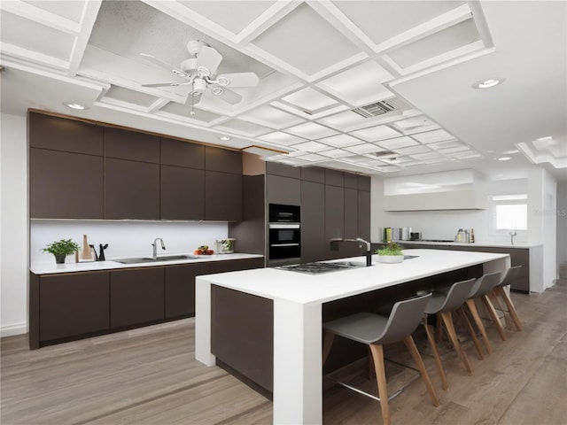 kitchen featuring modern cabinets, a sink, a kitchen bar, light wood-style floors, and light countertops