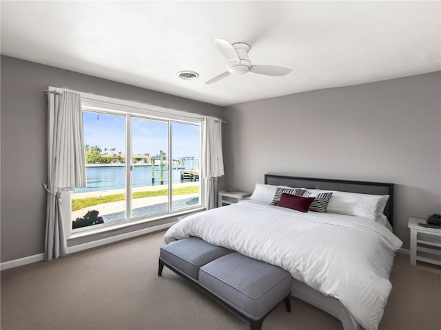 carpeted bedroom featuring a water view, baseboards, and a ceiling fan