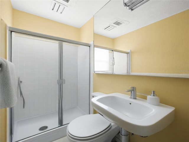 bathroom featuring a stall shower, toilet, and a sink