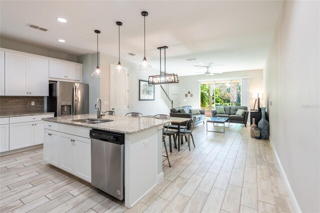 17847 Althea Blue Pl, Lutz, FL 33558 - kitchen featuring stainless steel appliances, a sink, a ceiling fan, backsplash, and light wood-type flooring