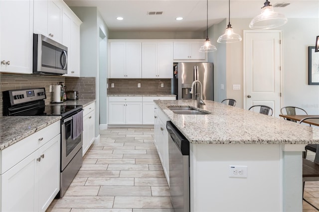 17847 Althea Blue Pl, Lutz, FL 33558 - kitchen with appliances with stainless steel finishes, a sink, a breakfast bar, backsplash, and an island with sink