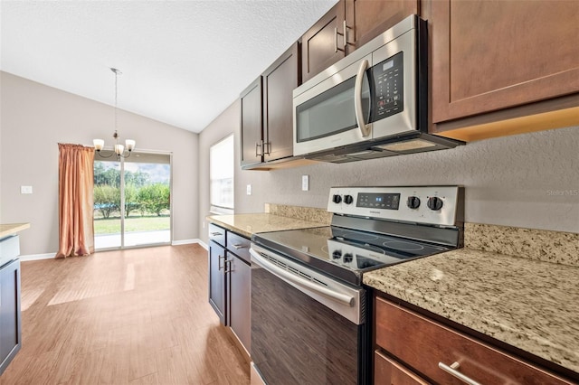 6937 Gideon Cir, Zephyrhills, FL 33541 - kitchen with stainless steel appliances, light wood-style flooring, a chandelier, lofted ceiling, and baseboards