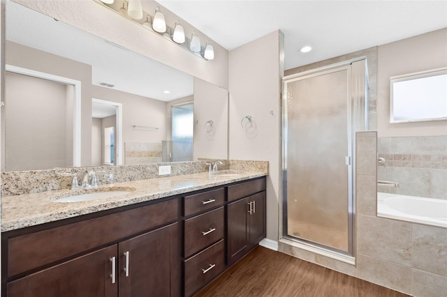 6937 Gideon Cir, Zephyrhills, FL 33541 - bathroom featuring double vanity, a garden tub, a stall shower, and wood finished floors