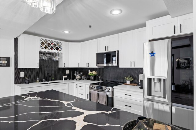 219 4th Ave N Unit 201, Saint Petersburg, FL 33701 - kitchen featuring appliances with stainless steel finishes, a sink, decorative backsplash, light stone counters, and white cabinets