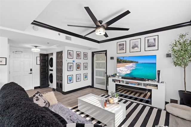 219 4th Ave N Unit 201, Saint Petersburg, FL 33701 - living area featuring estacked washer and dryer, crown molding, a ceiling fan, light wood-style flooring, and baseboards