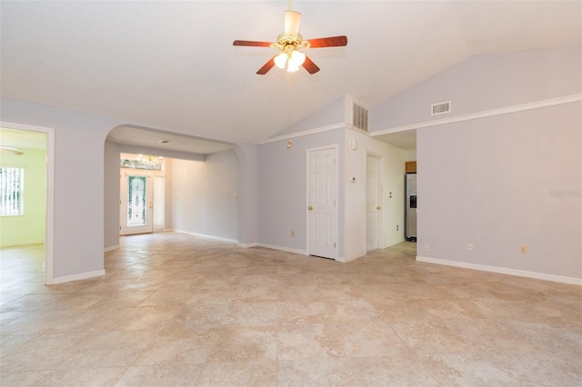 empty room featuring arched walkways, a ceiling fan, vaulted ceiling, and baseboards