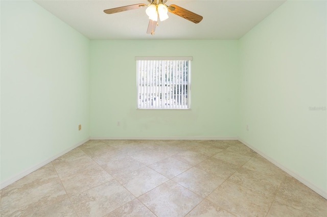 tiled empty room featuring ceiling fan and baseboards