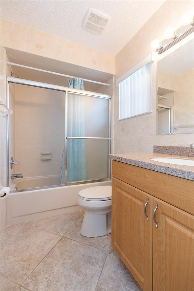 bathroom with toilet, shower / bath combination with glass door, vanity, tile patterned flooring, and a textured ceiling