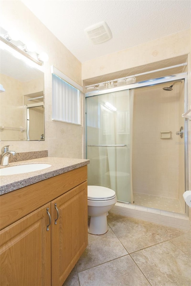 bathroom featuring tile patterned floors, a stall shower, toilet, and vanity