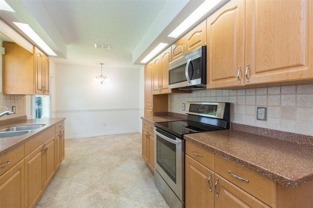kitchen featuring appliances with stainless steel finishes, a sink, tasteful backsplash, dark countertops, and decorative light fixtures