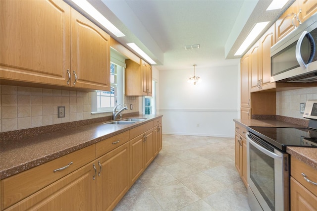 kitchen with appliances with stainless steel finishes, a sink, dark countertops, tasteful backsplash, and hanging light fixtures