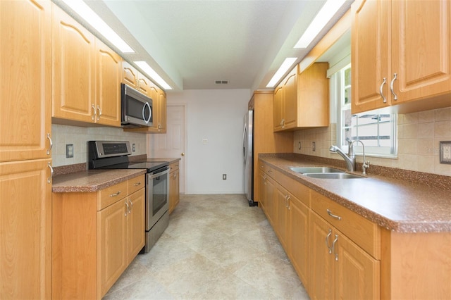 kitchen featuring appliances with stainless steel finishes, a sink, tasteful backsplash, and baseboards