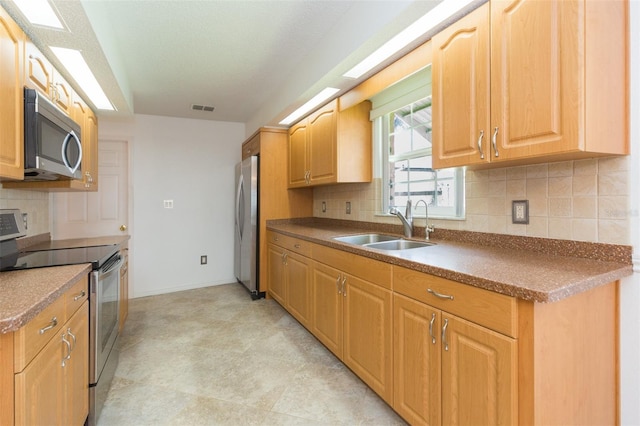kitchen featuring appliances with stainless steel finishes, a sink, baseboards, decorative backsplash, and dark countertops