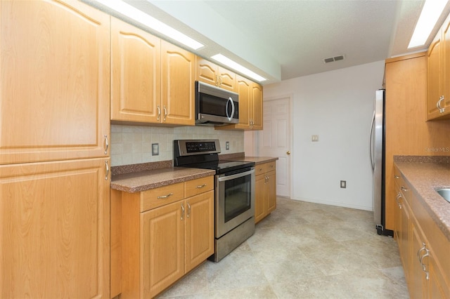 kitchen featuring appliances with stainless steel finishes, decorative backsplash, and baseboards