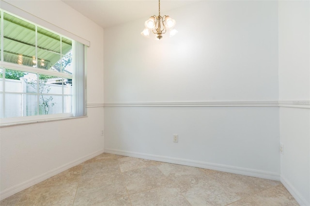 spare room with a chandelier and baseboards