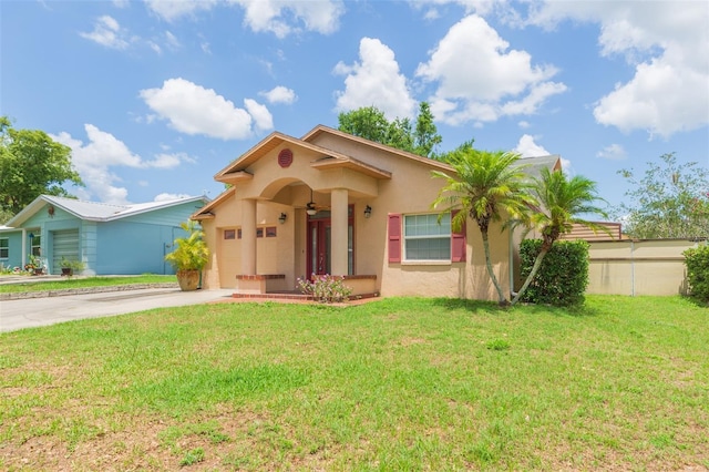 mediterranean / spanish-style house with stucco siding, concrete driveway, a front yard, a garage, and a ceiling fan