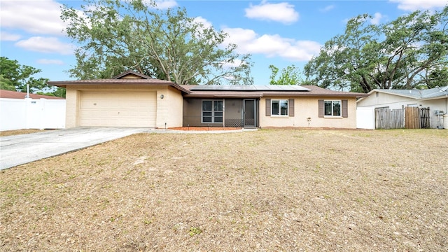 ranch-style house featuring brick siding, an attached garage, driveway, and solar panels