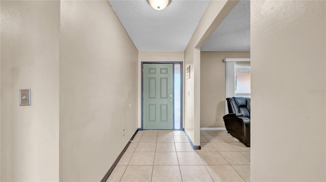 foyer entrance with baseboards, a textured ceiling, and light tile patterned flooring