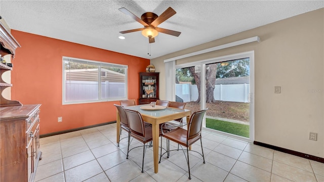 dining area with baseboards, ceiling fan, a textured ceiling, and light tile patterned flooring