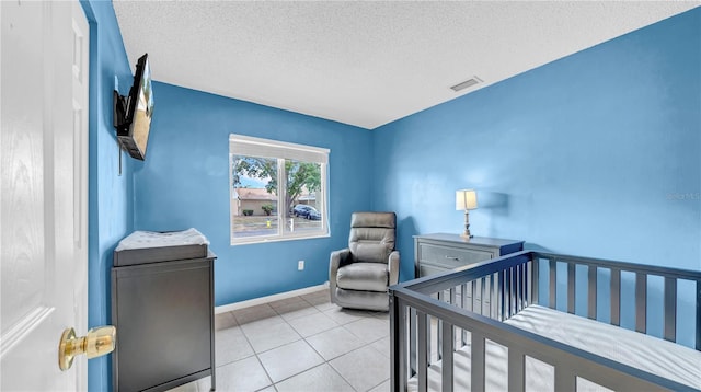 tiled bedroom with a textured ceiling, a nursery area, and baseboards