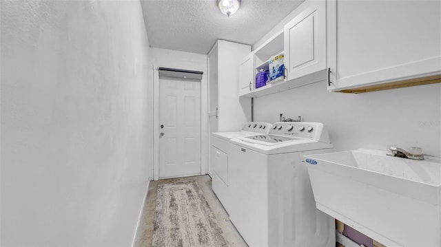 clothes washing area featuring cabinet space, washer and dryer, and a textured ceiling
