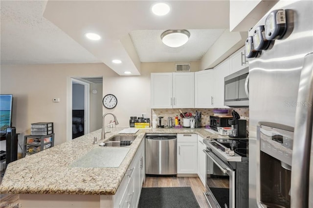 5321 Summerlin Rd Unit 2108, Fort Myers, FL 33919 - kitchen with stainless steel appliances, a peninsula, a sink, light wood-style flooring, and white cabinets