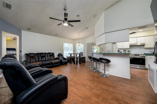 10149 Briar Cir, Hudson, FL 34667 - living room with a textured ceiling, ceiling fan, wood finished floors, a chandelier, and lofted ceiling