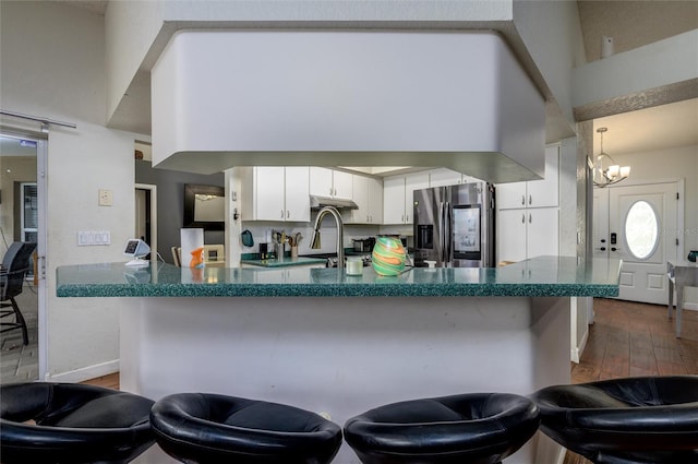 10149 Briar Cir, Hudson, FL 34667 - kitchen featuring stainless steel refrigerator with ice dispenser, under cabinet range hood, dark wood finished floors, dark countertops, and white cabinetry
