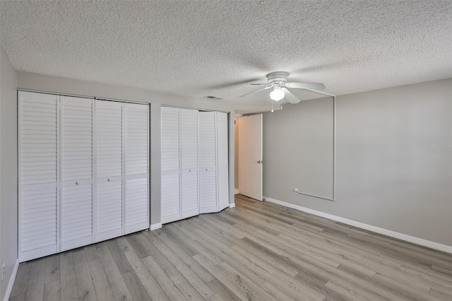 4801 W Mcelroy Ave Unit D104, Tampa, FL 33611 - unfurnished bedroom featuring multiple closets, light wood-style floors, baseboards, and a textured ceiling