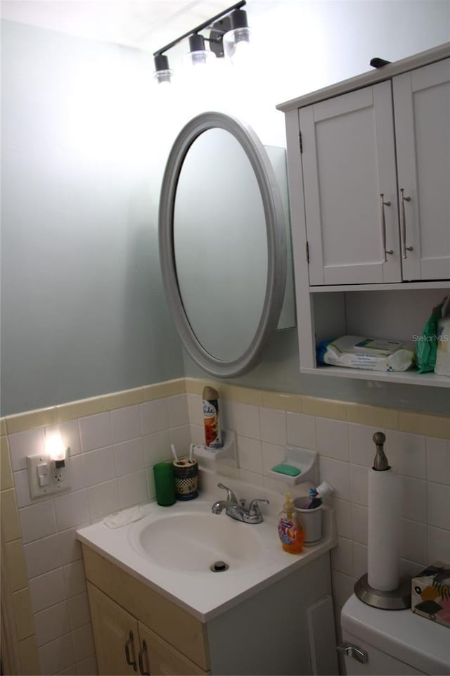 2020 World Parkway Blvd Unit 12, Clearwater, FL 33763 - half bathroom with tile walls, toilet, vanity, and wainscoting