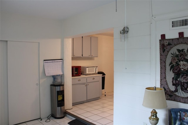 2020 World Parkway Blvd Unit 12, Clearwater, FL 33763 - kitchen with white microwave, light tile patterned floors, gray cabinetry, and light countertops