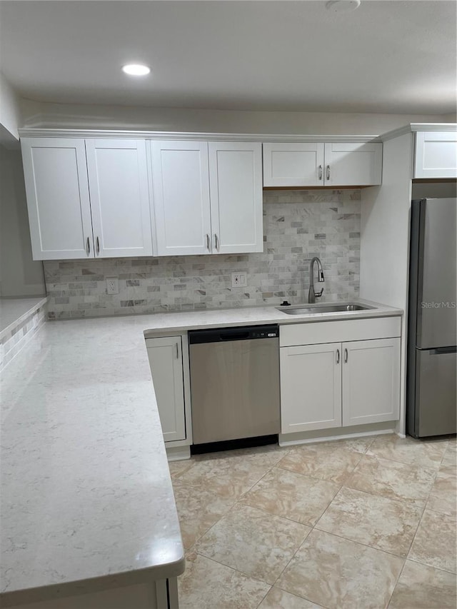 kitchen featuring appliances with stainless steel finishes, a sink, light countertops, backsplash, and white cabinetry