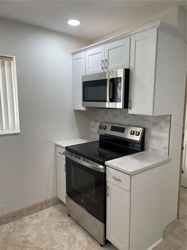 kitchen featuring appliances with stainless steel finishes, baseboards, light countertops, and tasteful backsplash