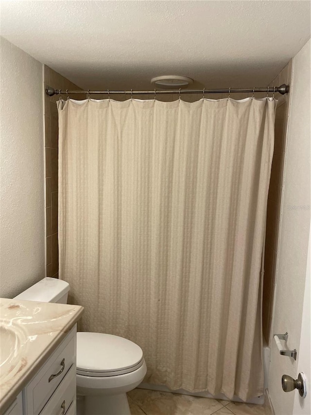 full bath featuring vanity, toilet, tile patterned floors, curtained shower, and a textured ceiling